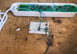 Disassembled Gembird TSL-PS-F4U-01-W power strip with visible circuit board and a breadboard connected via jumper wires.