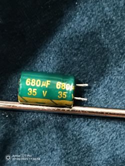 Zielony kondensator elektrolityczny 680 µF 35 V leży na granatowym materiale