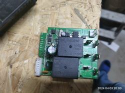 Płytka drukowana z przekaźnikami i komponentami elektronicznymi na drewnianym tle.
