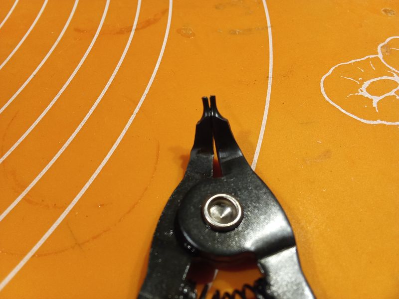 Czarne szczypce do pierścieni Segera na pomarańczowym tle.