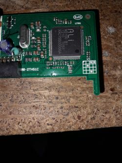 PCB with ALi M3100 B1 chip and various SMD components on a wood surface