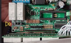Płytka PCB z elektroniką, widoczna podstawka mikrokontrolera, zworki oraz wskazanie portu Q1 żółtą strzałką.