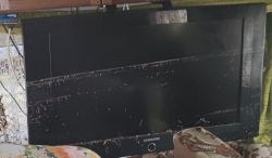 Flood-Damaged Samsung TV with Mud-Stained Screen Flood-damaged Samsung TV with visible mud stains on the screen.