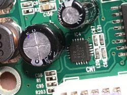 Zbliżenie na płytkę PCB z elementami elektronicznymi, w tym kondensatorami i układem scalonym.