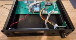 View of the interior of a prototype device with a mounted PCB and wiring inside a case.