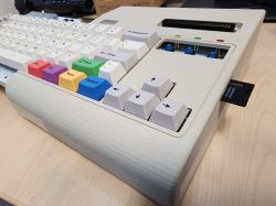 Zbliżenie na klawiaturę retro komputera z kolorowymi klawiszami funkcyjnymi i kartą SD wsuniętą z boku.