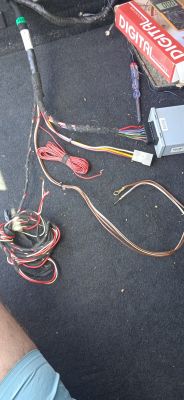 Wiązka kabli i narzędzia na dywaniku samochodowym.