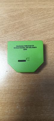 Green adapter labeled as Shelly Europe Ltd. product on wooden surface