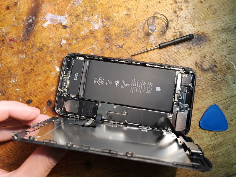iPhone Battery Replacement – Open Phone Open interior of a phone with visible battery and tools