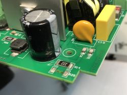 Close-up of a green printed circuit board with electronic components such as capacitors, resistors, and a coil.