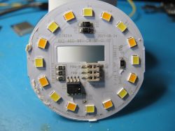 LED bulb PCB with multiple LED diodes and electronic components on a blue background.