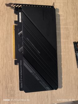 Karta rozszerzeń ASUS ROG Hyper M.2 leżąca na drewnianym stole.
