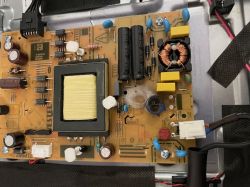 Zbliżenie na płytkę drukowaną prawdopodobnie z telewizora, z widocznymi różnymi komponentami elektronicznymi, w tym wyraźnie uszkodzonym warystorem.