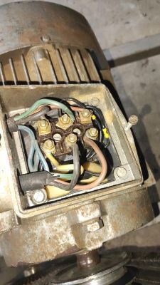 Zbliżenie na skrzynkę zaciskową silnika elektrycznego z podłączonymi przewodami.