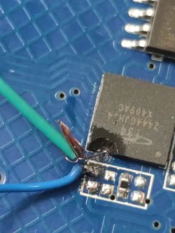 Close-up of blue PCB with green and blue wires soldered onto it