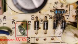 Close-up of a damaged circuit board with a bridge rectifier and thermistor.