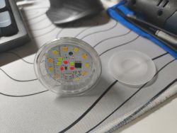 Colorful RGB LED bulb on a desk next to a translucent plastic cover