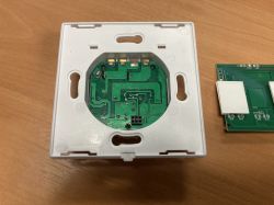 Printed circuit board in a plastic casing on a wooden surface.