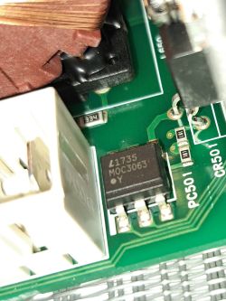 Zbliżenie na płytkę drukowaną z widocznym układem scalonym MOC3063, elementami SMD i fragmentem cewki.