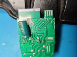 Close-up of a green printed circuit board with a soldered electrolytic capacitor.