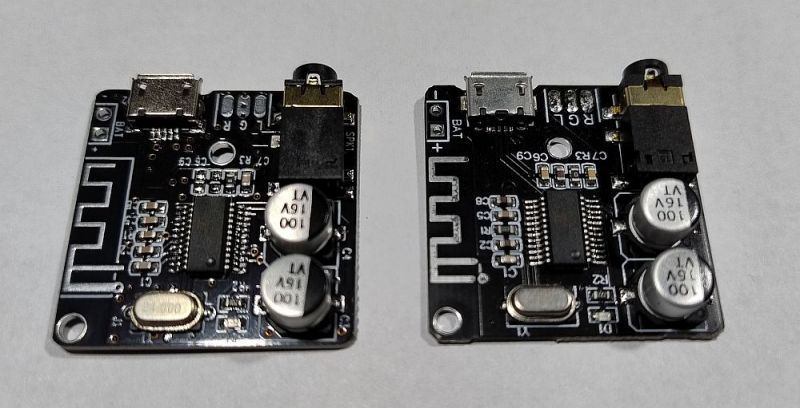 Dwa czarne moduły elektroniczne leżące obok siebie na białym tle, różniące się drobnymi szczegółami.