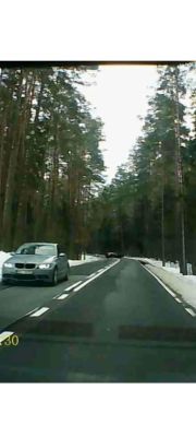Kadr z wideorejestratora: srebrny samochód na poboczu leśnej drogi zimą; tablica nieczytelna.