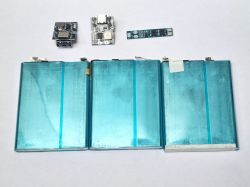 Ogniwa Li-Ion z elementami ładowarek USB-C na tle białego stołu.