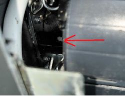 Zbliżenie mechanizmu w obudowie; czerwona strzałka wskazuje mały element na czarnej części