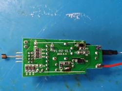 Zielona płytka PCB z elementami SMD i przewodami na niebieskiej macie roboczej