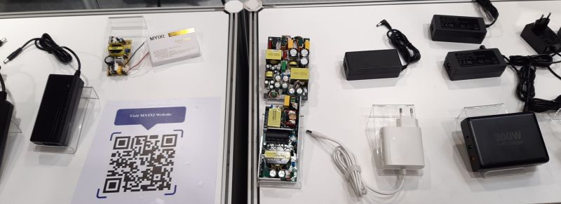 Stół wystawowy z różnymi ładowarkami i zasilaczami.