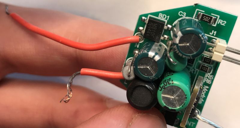 LED Power Supply Board with Connected Wire Close-up of an LED lamp power supply board with visible electrolytic capacitors, bridge rectifier, and a connected wire.