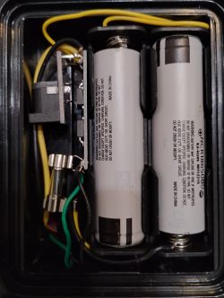 Doppelte Li-Ion-Batterie mit Sicherung Nahaufnahme von zwei Li-Ion-Batteriezellen in einem schwarzen Gehäuse, umgeben von Drähten und einer Sicherung.