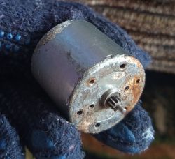 Zardzewiały mały silnik elektryczny trzymany w rękawiczce roboczej