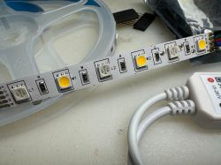 LED strip with wires and controller on a white surface.