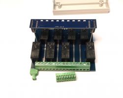 A printed circuit board with six relays and green screw terminal connectors.