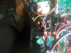 Wnętrze urządzenia elektronicznego z płytkami PCB, przewodami i dużym kondensatorem oraz rezystorem mocy