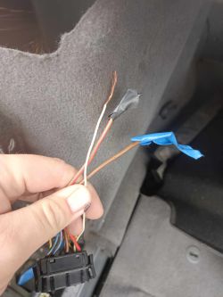 Zbliżenie na przewody samochodowe w bagażniku z uciętymi końcówkami i kostką.