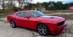 Red sports car parked on a concrete surface in an open area.