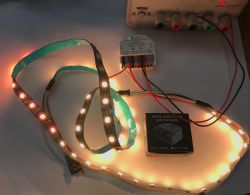 Lit LED strips lit on a table, connected to a Gledopto controller and bench power supply