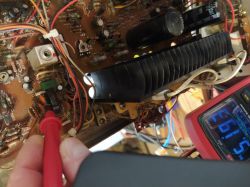 Zbliżenie na płytkę elektroniczną z przewodami, sondą pomiarową i multimetrem po prawej