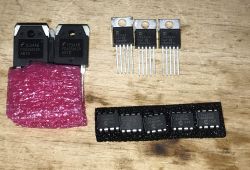 Various electronic components, including transistors and drivers, on a wooden background.