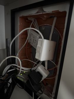 Recessed utility cabinet with cables and white modules; router and power supplies at the bottom