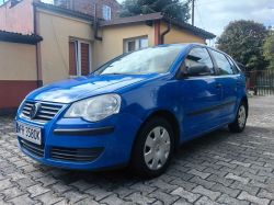 Blue Volkswagen Polo car parked on cobblestones in front of a building.