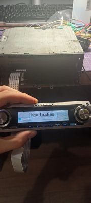 Panel radia Pioneer trzymany przed naprawionym urządzeniem z wyświetlaczem Now loading