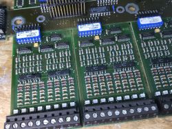 Close-up of a PCB with DIP switches, ICs, many resistors, and screw terminal blocks