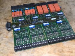 Three green PCBs with orange relays and screw terminal blocks on a wooden table