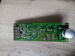 Zielona płytka PCB z wyświetlaczem 7‑segmentowym i dużym srebrnym pokrętłem na drewnianym tle