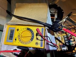 Cyfrowy miernik uniwersalny z wskazaniem oporu 8,62 MOhm, podłączony do wtyczki elektrycznej.