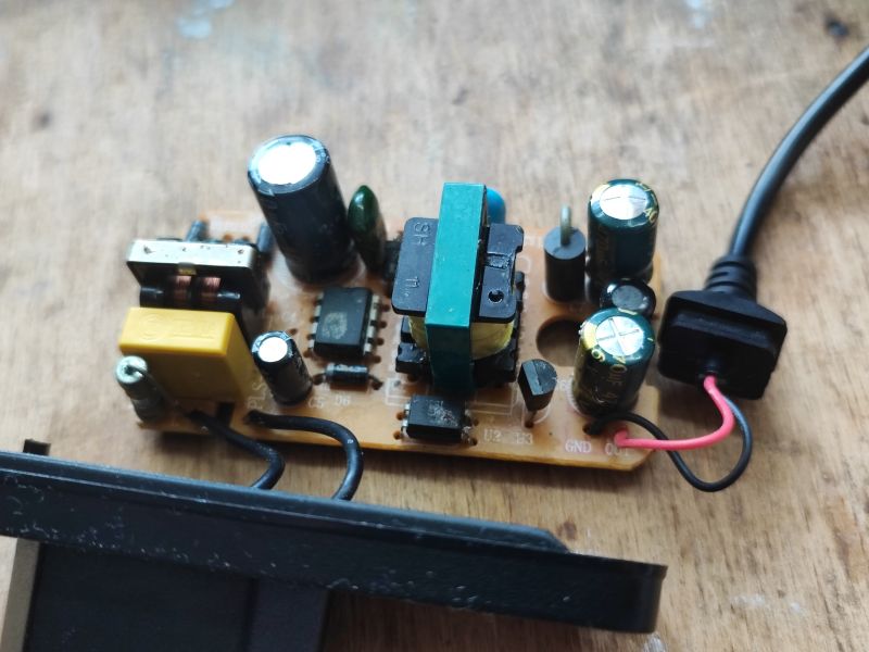 Widok wnętrza zasilacza impulsowego z widocznymi kondensatorami i transformatorami.