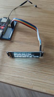 Small OLED display reads “webradio 1 Vol 4”, connected by a ribbon cable to a board on a table.